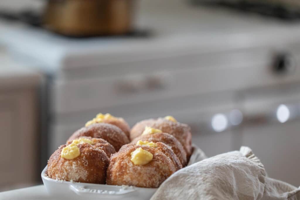 brioche donuts filled with custard in a casserole dish with a white oven in background