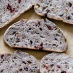 5 slices of sourdough cranberry bread layer out on parchment paper