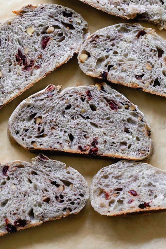 5 slices of sourdough cranberry bread layer out on parchment paper