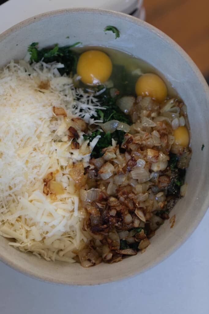 caramelized onions, eggs, cheese, and spinach in a ironstone bowl