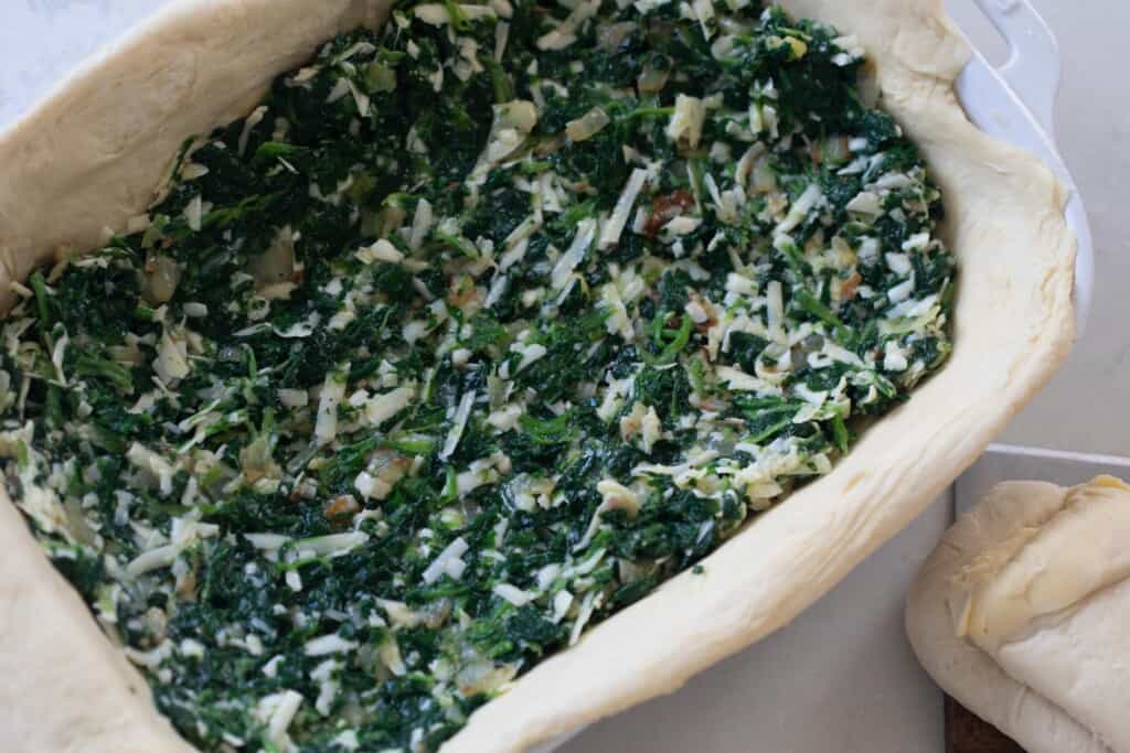 spinach filling added to a baking dish lined with parchment paper