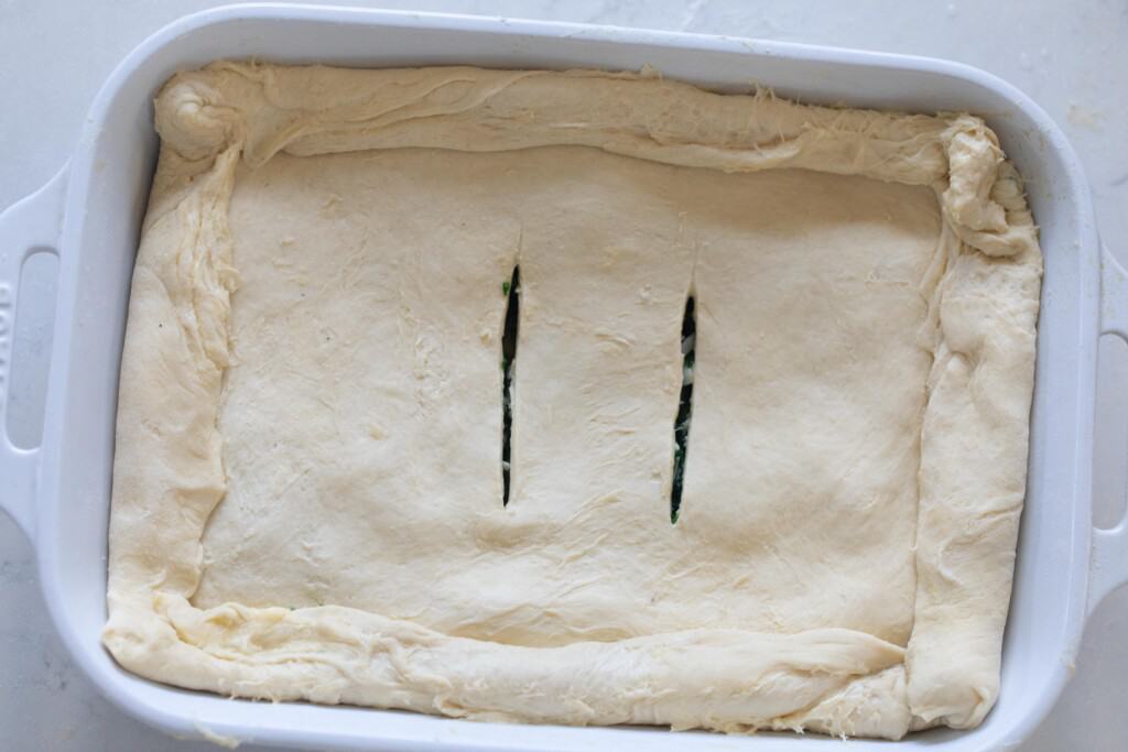 overhead photo of a unbaked spinach pie in a white baking dish
