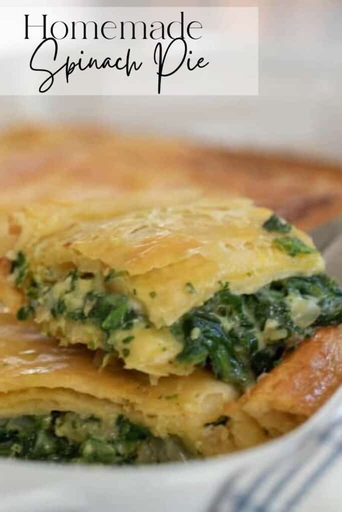 close up picture of a slice of spinach pie on top of the rest of the pie in a white baking dish