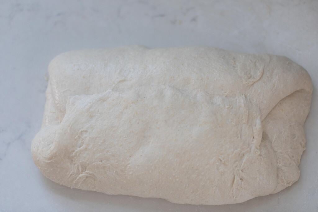 high hydration sourdough dough on a white countertop folded in for the second shape