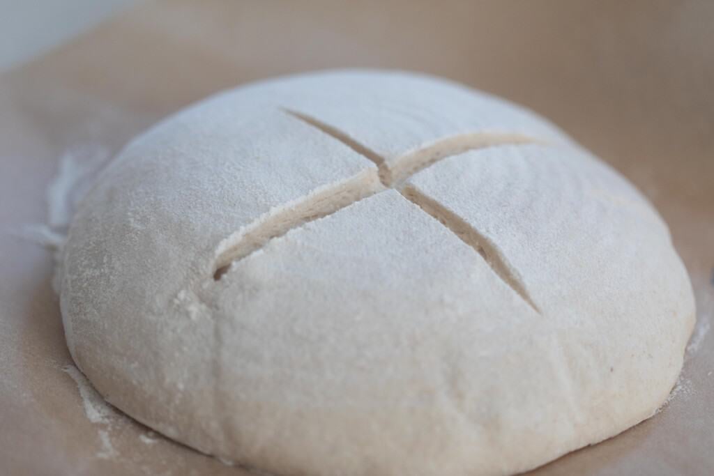 scored high hydration sourdough dough on parchment paper