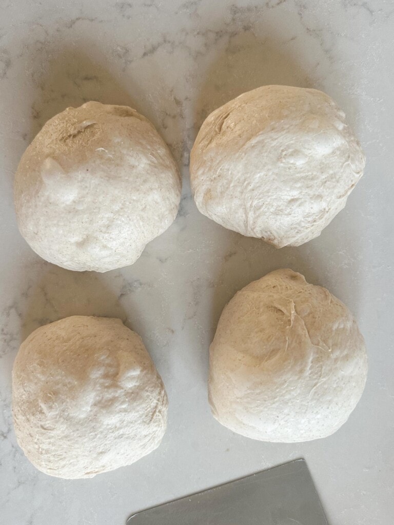 four mini sourdough loaf dough balls after rising at room temp