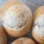 4 mini sourdough loaves next to each other on a wire rack on top of a white countertop