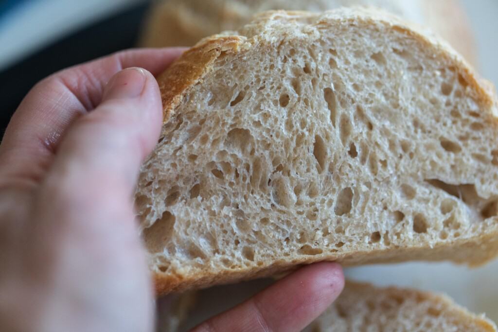 hand holding a mini sourdough loaf that has been sliced to make the perfect sandwich sized slice