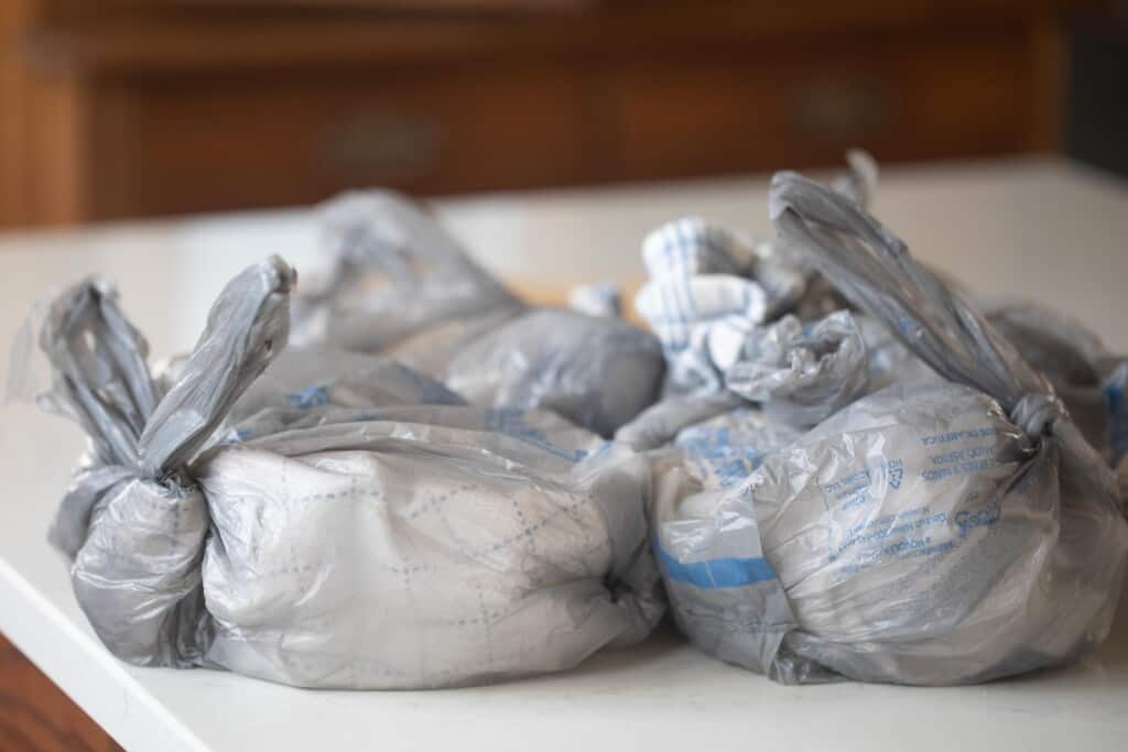 bowls of sourdough bread in plastic grocery bags on a white countertop