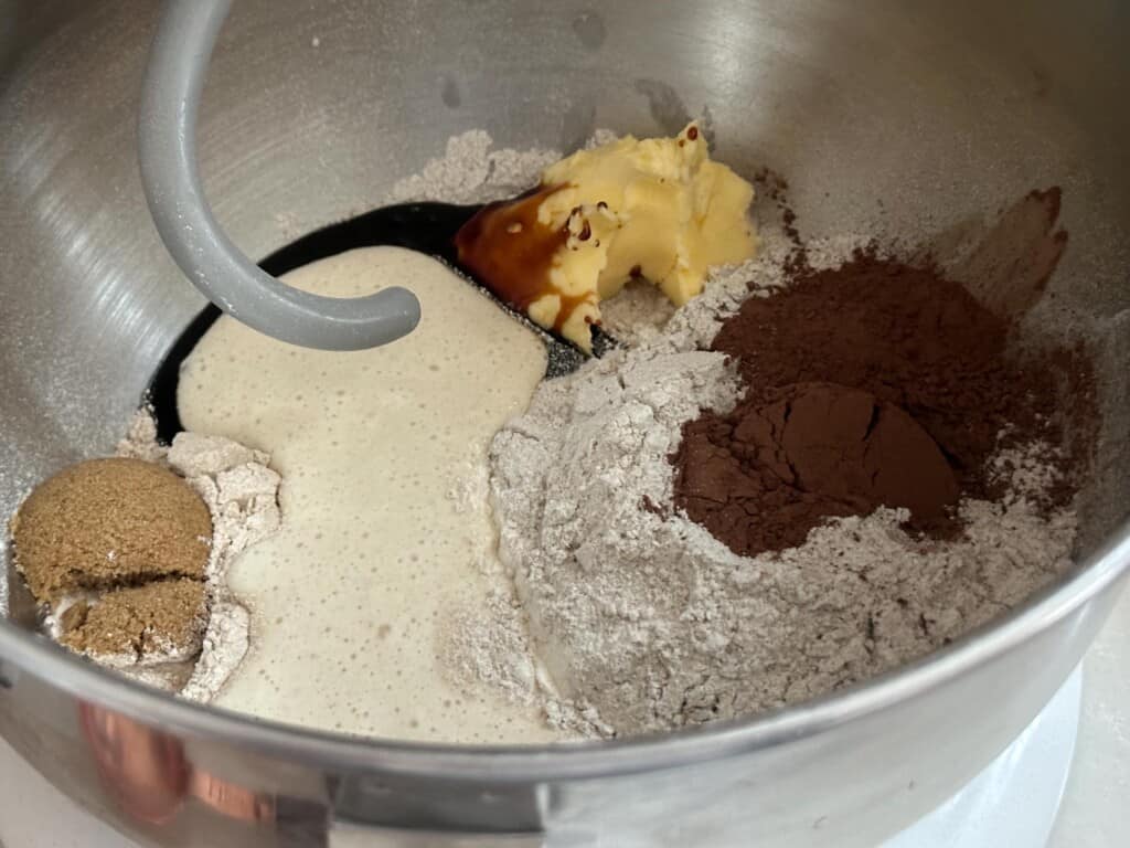 flour, sourdough starter, brown sugar, and cocoa powder in a stand mixer bowl with dough hook