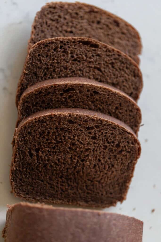 overhead photo of four slices of sourdough pumpernickel bread laying on a white countertop