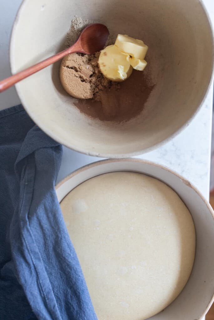 Doug in a bowl next to cinnamon, sugar, and butter in a bowl