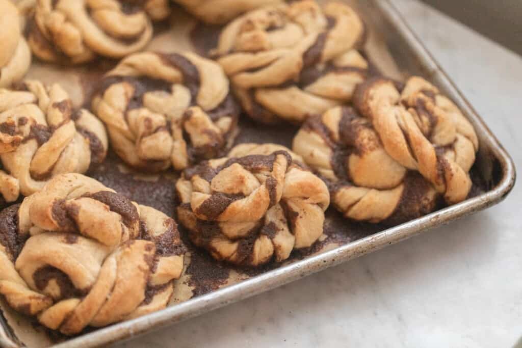 Swedish cinnamon buns on a cookie sheet on a white countertop