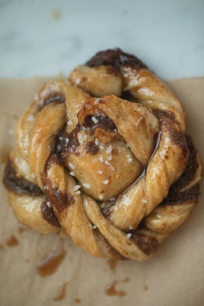 overhead photo of a sourdough Swedish cinnamon bun topped with pearled sugar on parchment paper