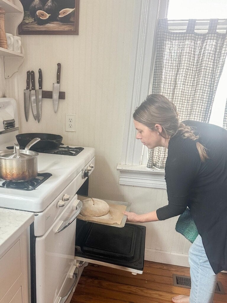 Woman placing a baking stone in an oven to bake a sourdough boule