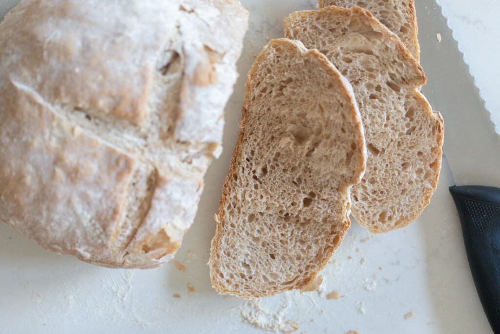 Sourdough loaf made without a dutch oven and cut into with two slices laying down on white countertop