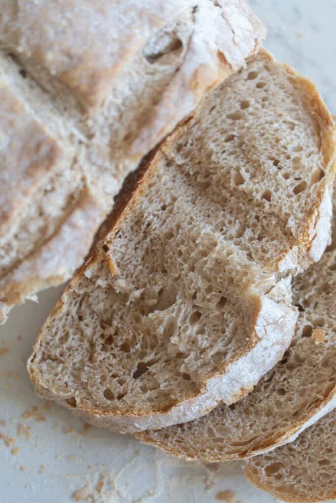 A loaf of sourdough bread baked without a Dutch oven cut into 