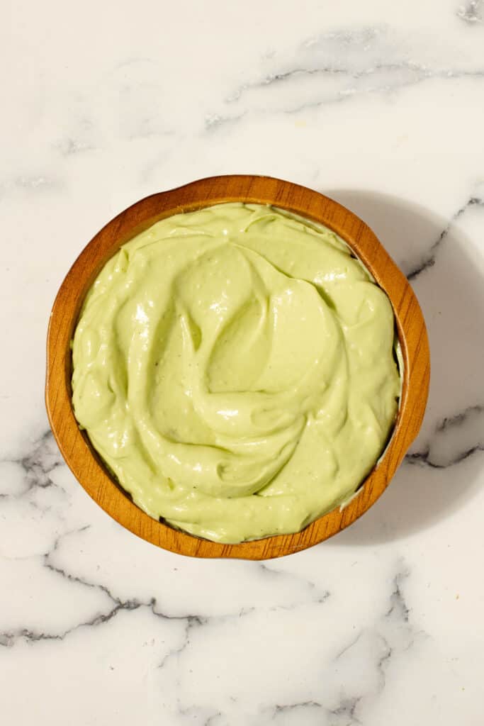 Avocado aioli in a terracotta bowl on a white countertop