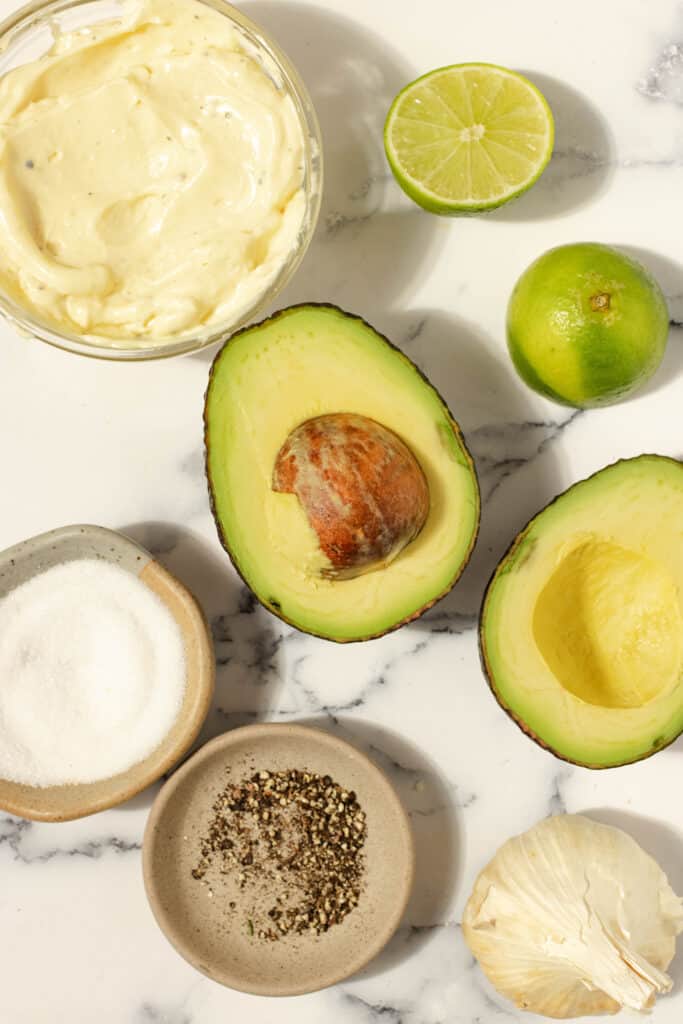 avocado aioli ingredients, including an avocado, salt, pepper, lime, garlic and mayo