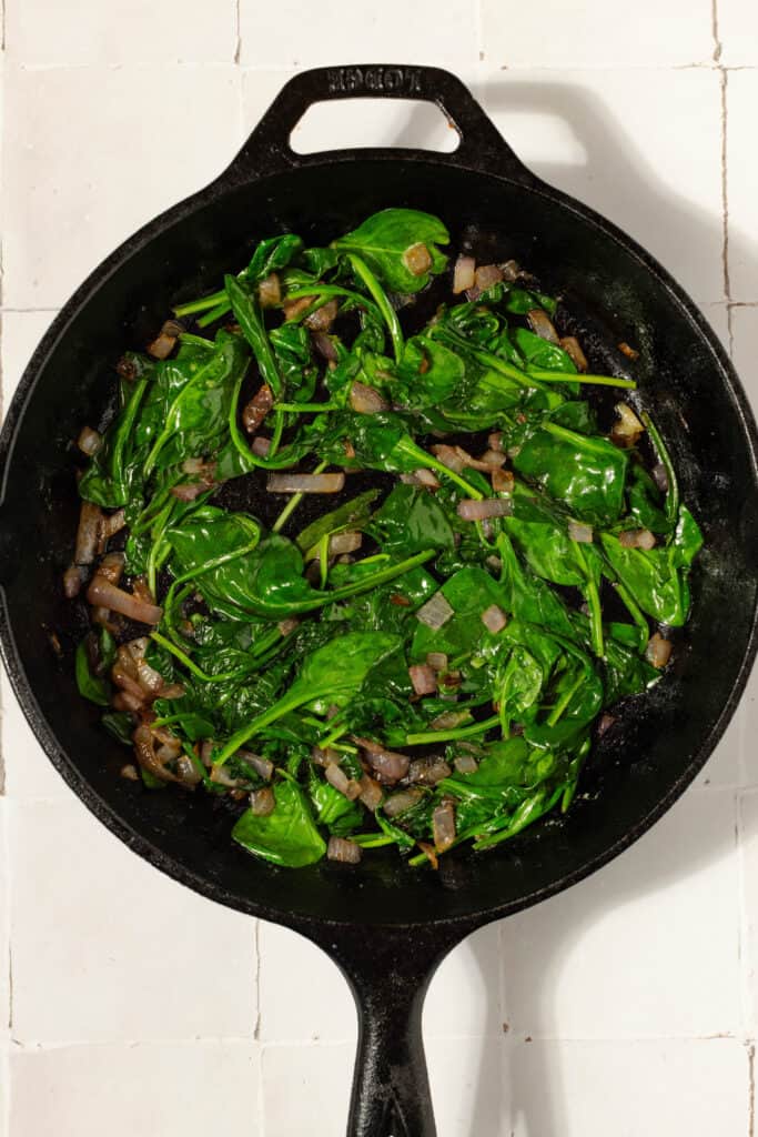 Cast iron skillet with sauted onions and spinach