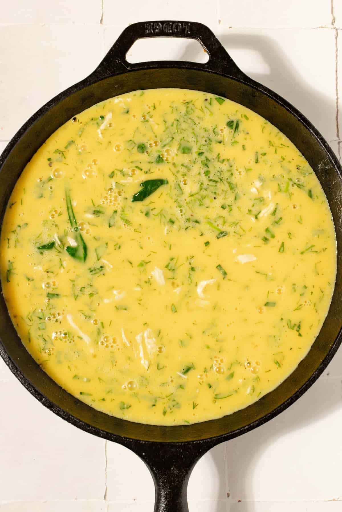 Cast iron skillet with egg mixture ready for the oven