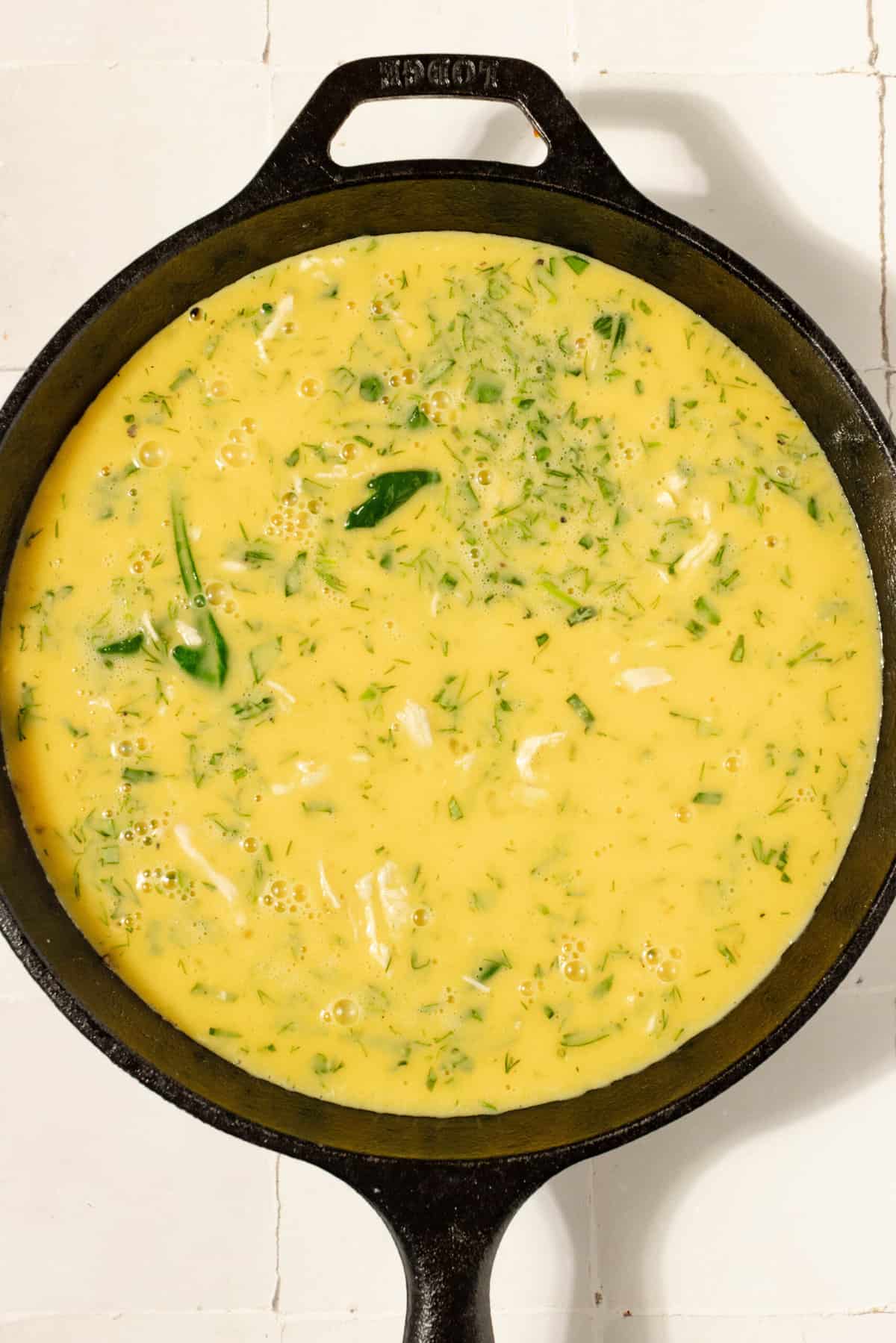Cast iron skillet with egg mixture ready for the oven