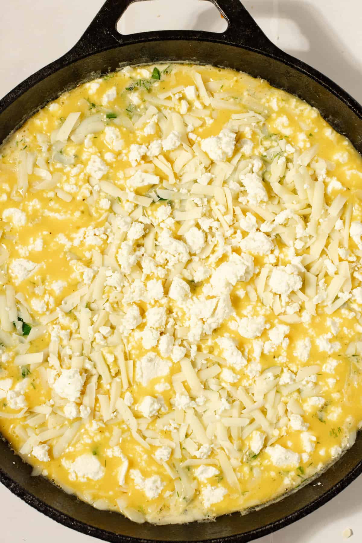 Chicken frittata ready for oven in a cast iron skillet