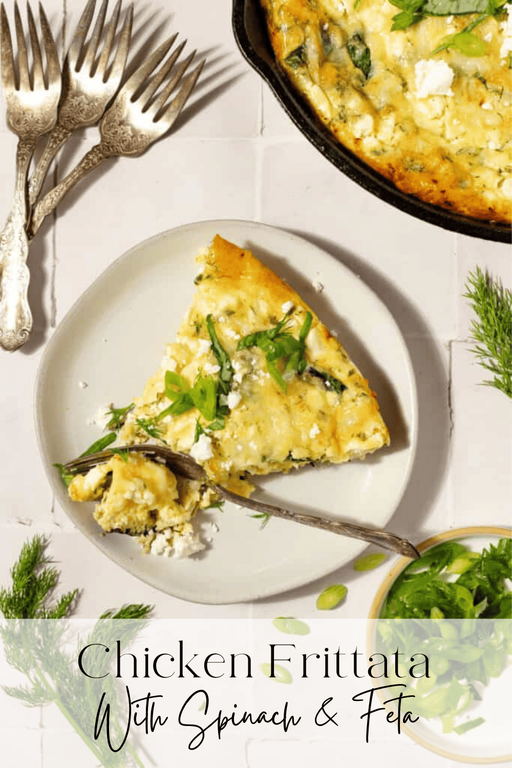 Overhead view of a slice of chicken frittata on a white plate with 3 forks in background and cast iron skillet and fresh herbs on a cream countertop