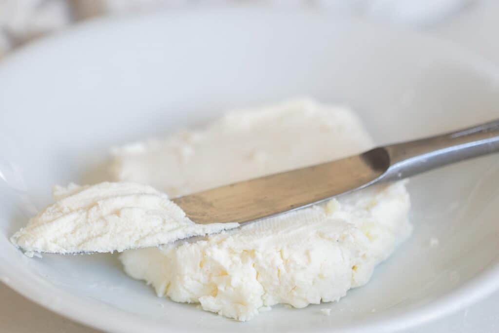 Kefir cheese on a white plate with a silver butter knife dipped in it