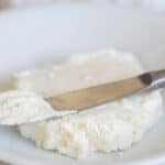 Kefir cheese on a white plate with a silver butter knife dipped in it
