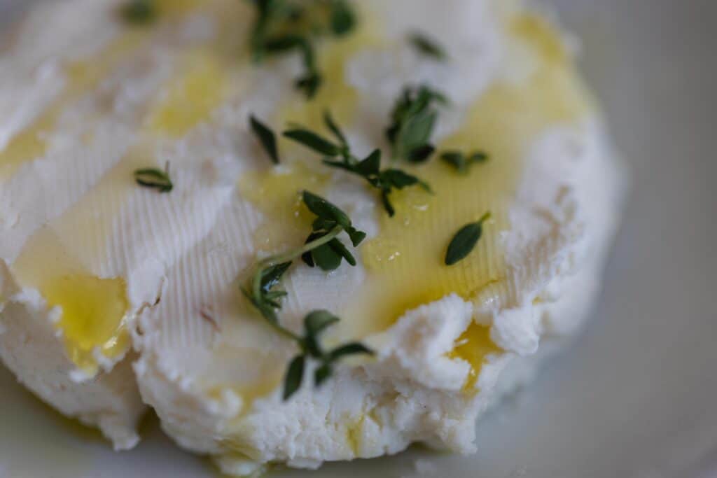 Close up of kefir cheese drizzled with olive oil and sprinkled with fresh herbs