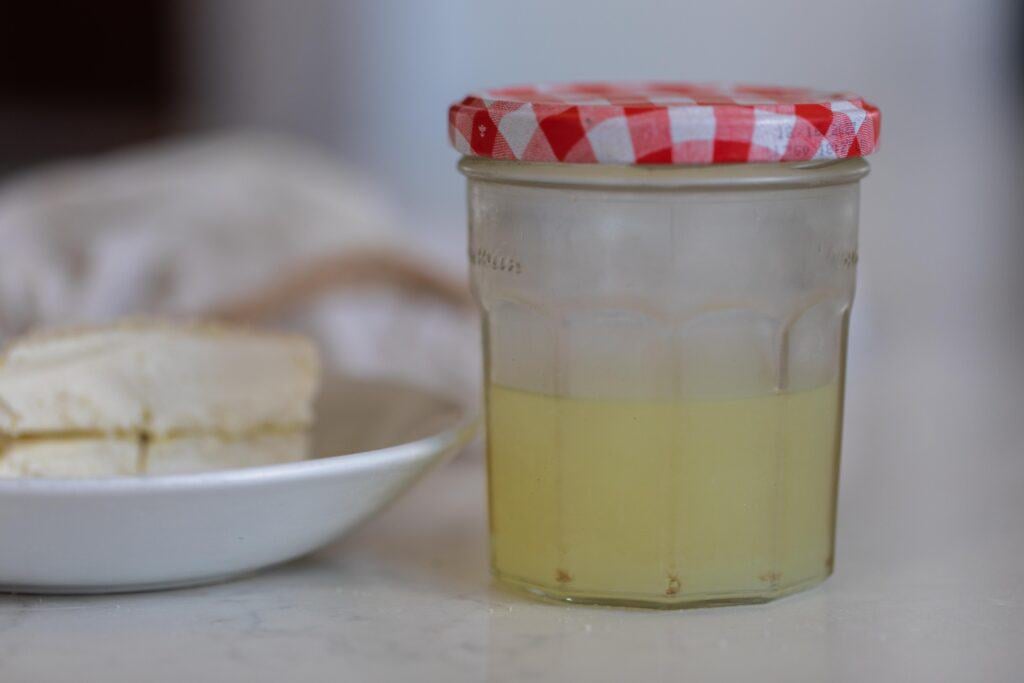 kefir cheese on a white plate next to a jar full of kefir whey