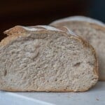 Two halves of a low hydration sourdough bread on a white countertop