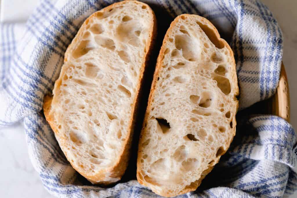 Two slices of small batch sourdough bread in a blue and white tea towel lined basket