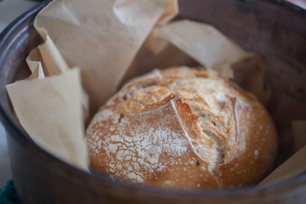 loaf off sourdough bread in a parchment lined dutch oven