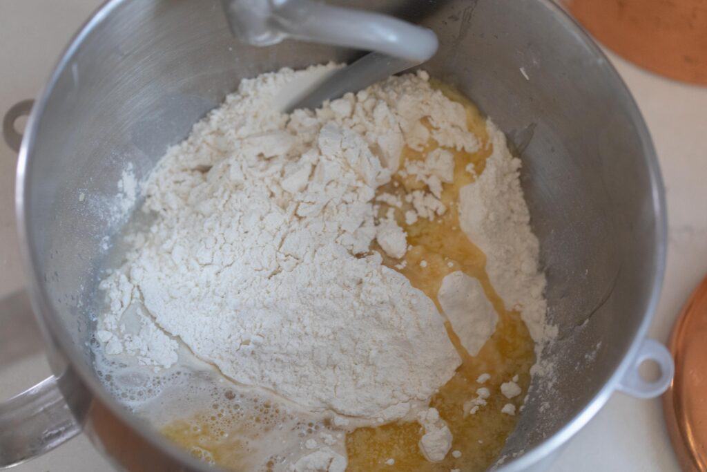 flour, melted butter, sourdough starter, water, and yeast in a stand mixer bowl