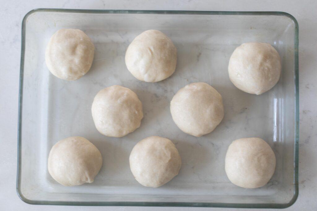overhead photo of sourdough rolls in a glass baking dish on a white countertop