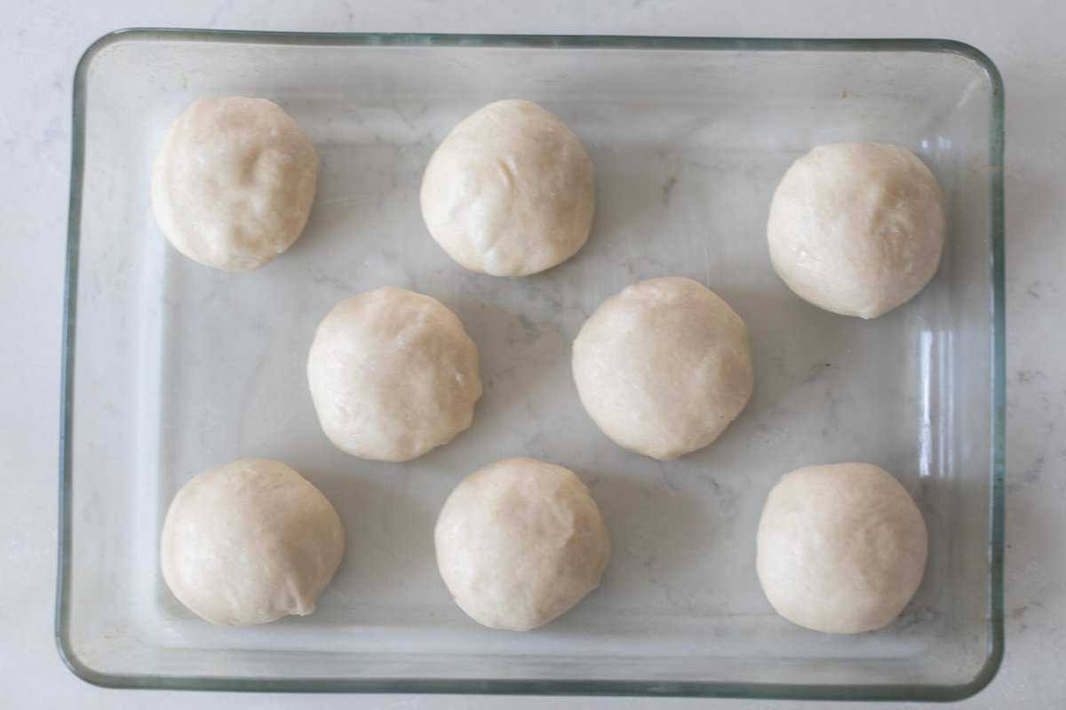 overhead photo of sourdough rolls in a glass baking dish on a white countertop