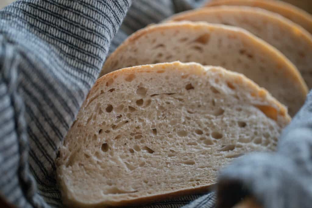 four slices of sourdough Italian bread wrapped in a blue and white stripped towel