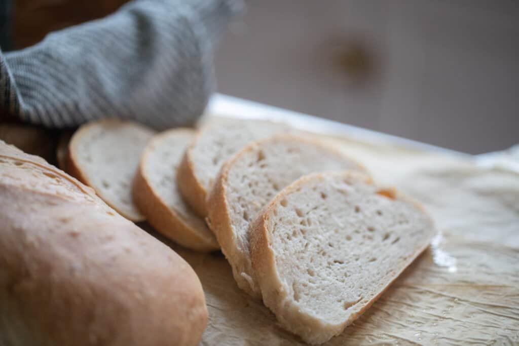 four slices of bread next to a loaf of bread on parchment paper 