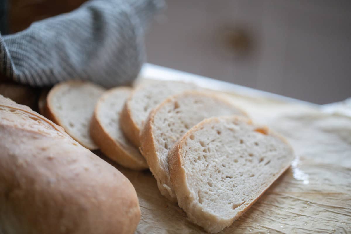 four slices of bread next to a loaf of bread on parchment paper