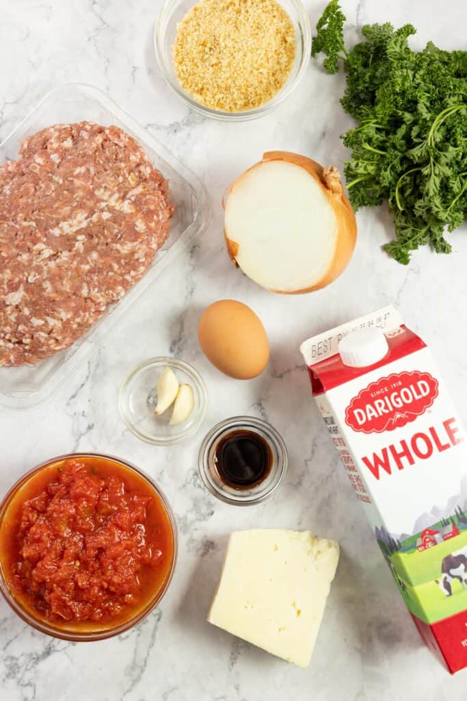 pork, milk, parsley, egg, cheese, and other ingredients on a countertop