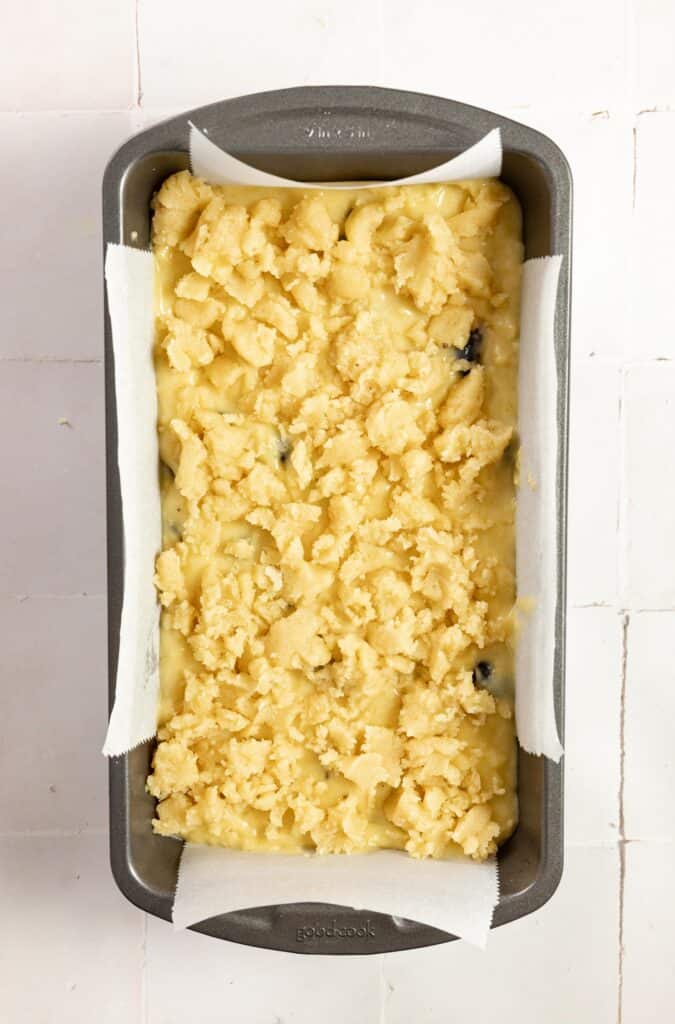 Sourdough blueberry bread batter in a loaf pan with a crumble top ready for the oven