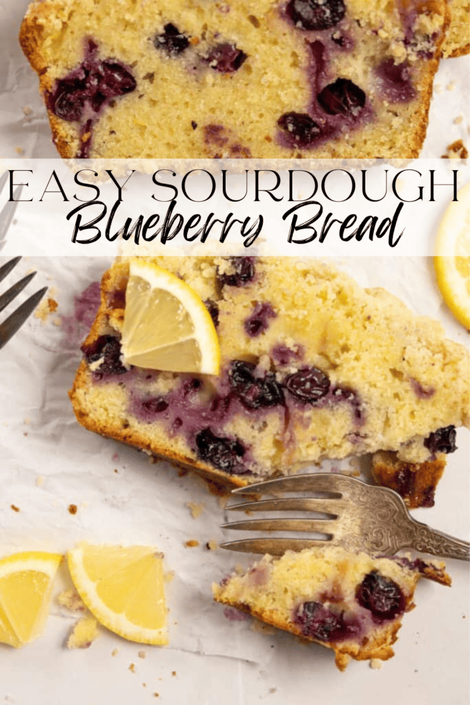 A slice of sourdough blueberry bread with a lemon wedge on top and a silver fork slicing into it