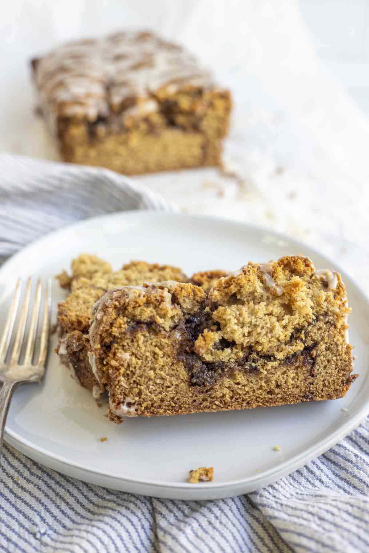 two slices of cinnamon swirl bread on a plate with the rest of the loaf in the background