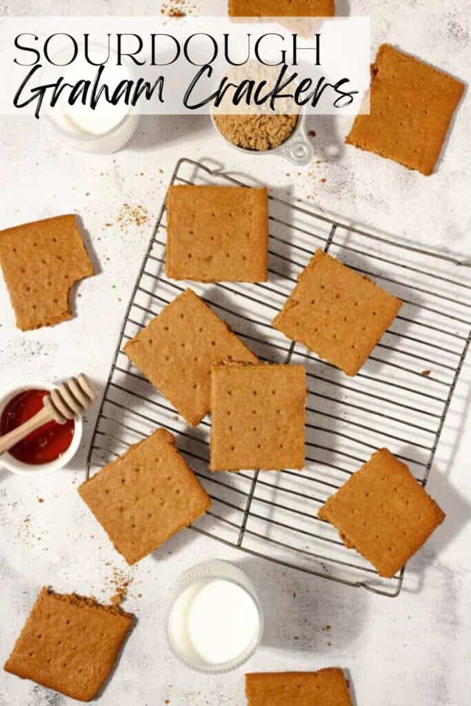 overhead photo of graham crackers spread allover a countertop and wire cooling rack with glasses of milk and honey surrounding the crackers