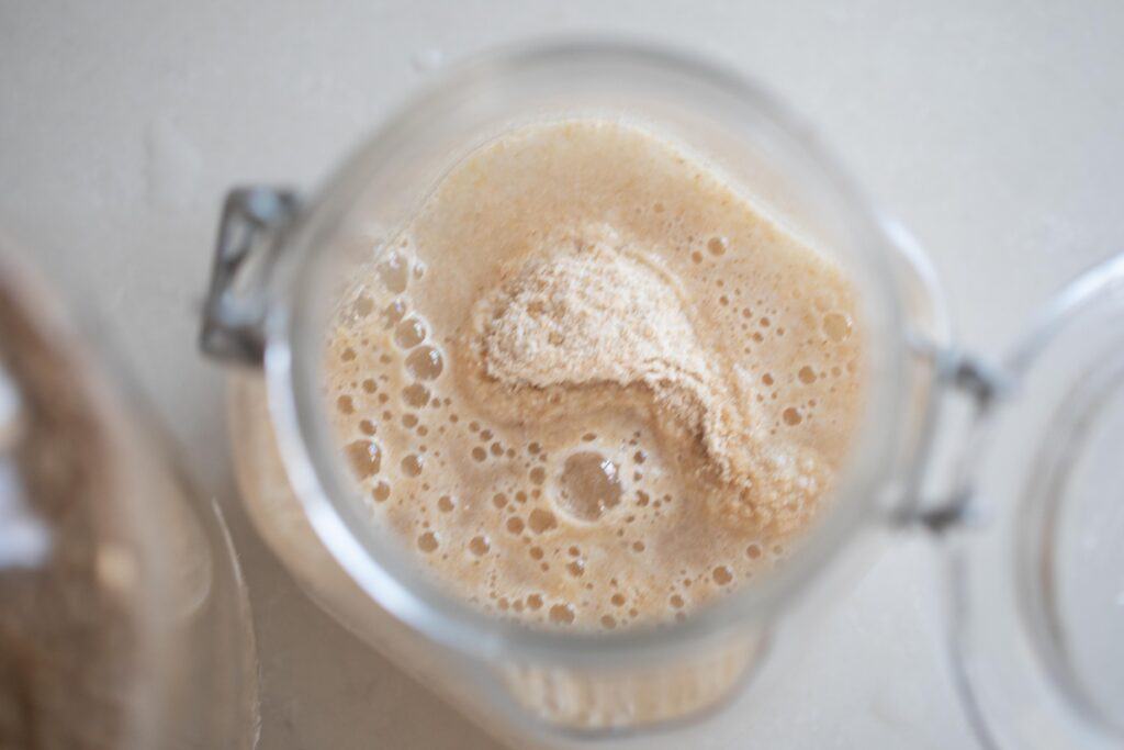 water and whole wheat flour in a jar on a white countertop