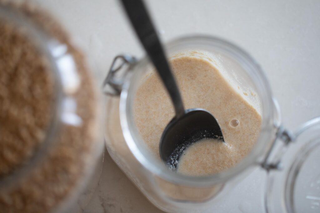 a spoon inside a jar of whole wheat sourdough starter.