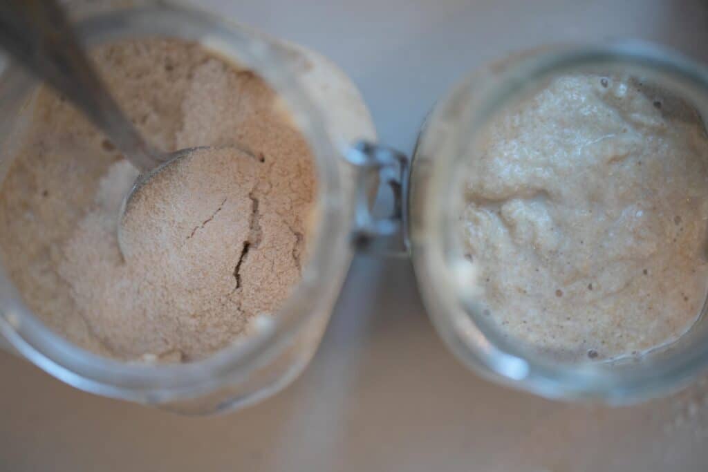 one jar of whole wheat flour next to a jar of sourdough starter