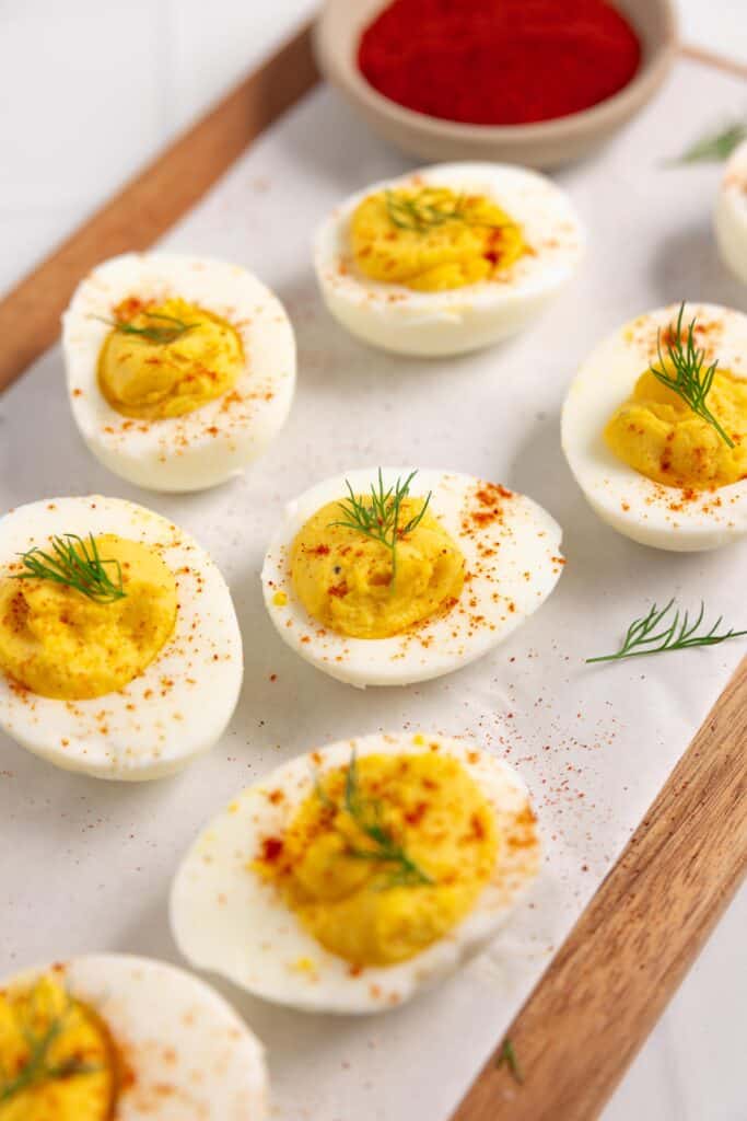 6 deviled eggs on white parchment paper over a wood cutting board
